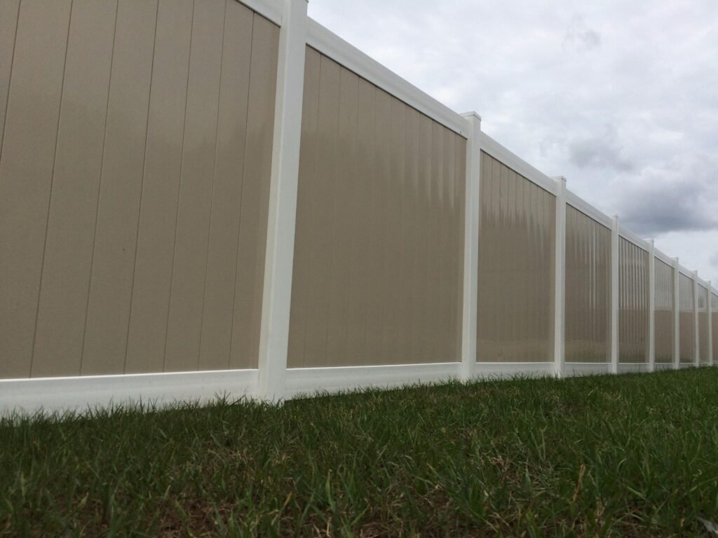 Tan and white vinyl privacy fence along a property line